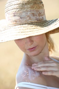 Closeup of beautiful woman spreading sunscreen on her shoulder