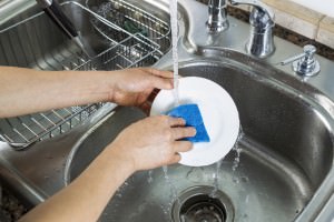 Female hands washing single white dinner plate